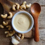 Dairy-Free Cheese Sauce in a ceramic bowl with cashews and garlic